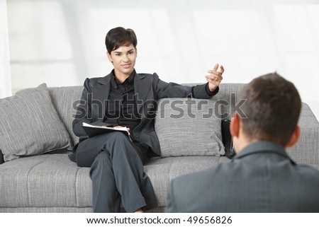 Business meeting at office. Businesswoman sitting on sofa having job interview, smiling.