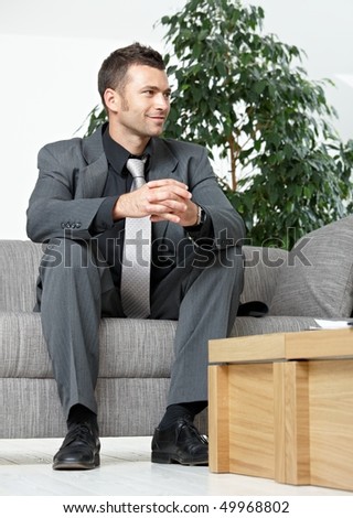 People at office. Businessman sitting on sofa, listening to business partner. Low angle view.