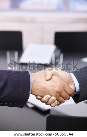 Closeup of hands. Businessmen shaking hands over table, in office meeting room.