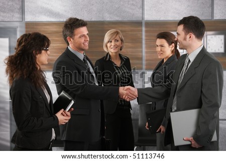 Happy businesspeople shaking hands greeting each other before business meeting in office.