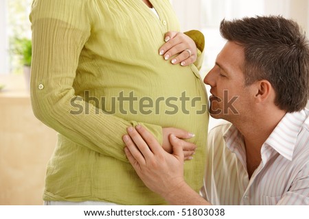 stock photo Man talking to baby in expecting wife's tummy stroking wife's