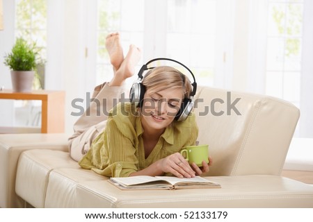 stock photo Woman drinking coffee lying on couch reading book wearing 