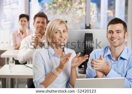 Happy business people sitting at desk in classrom, and clapping at the end of business training.