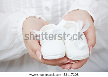 Closeup picture of new baby shoes in expectant mother\'s hands.