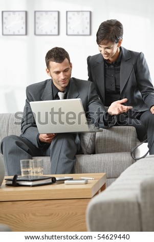 Young business people having meeting at office sitting on couch working on laptop computer.