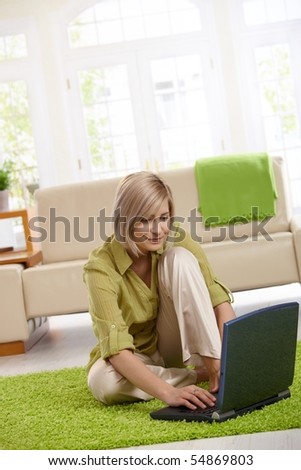 Smiling woman surfing the internet on laptop computer at home.