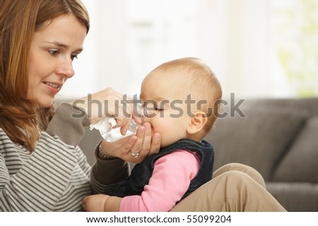 Happy mum holding baby girl in arms smiling baby drinking from feeding bottle.?