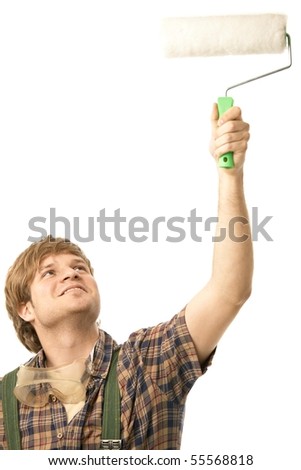 Young man painting wall using paint roller, smiling. Isolated on white.