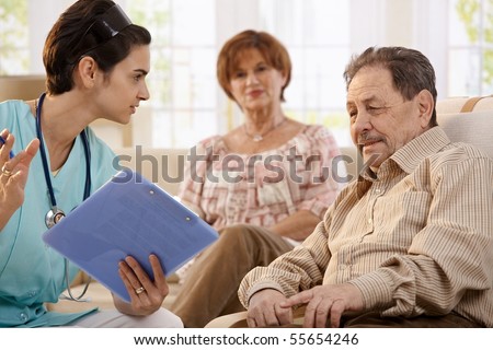 Nurse talking with elderly people showing test results during routine examination at home.