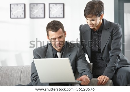 Young business people having meeting at office sitting on couch working on laptop computer.
