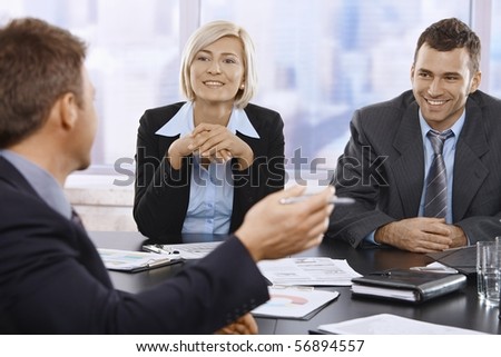Smilling businesspeople at meeting table in office.?