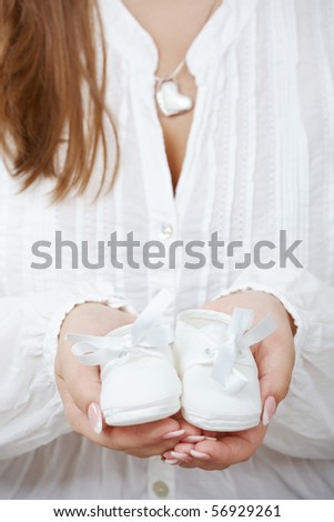 Closeup picture of new baby shoes in expectant mother\'s hands.