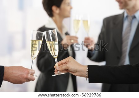 Business people raising toast with champagne at office, focus placed on flutes.