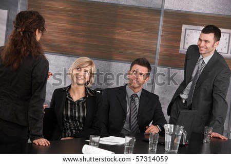 Well dressed businesspeople talking in meeting room, smiling.?