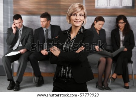 Portrait of confident young businesswoman standing in office hallway, arms crossed, smiling.?