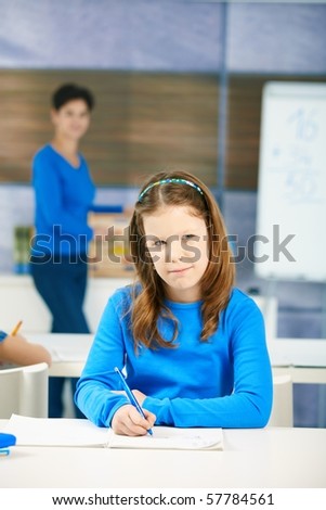 Portrait of young schoolgirl thinking what to write at class test, looking up.?