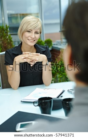 Happy young businesswoman sitting outdoor on office terrace and talking, smiling. Over the shoulder view.