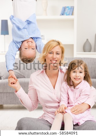 Family fun. Mother holding her daughter on knees, boy hangging upside down.