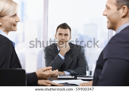 Young professional listening to colleagues conversation in office.?