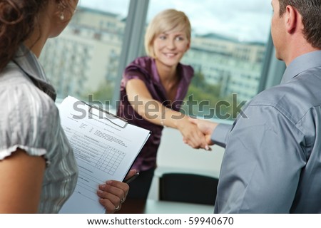 Successful job interview - happy employee shaking hands, smiling. Focus places on questionnarie in front, reults are excellent.