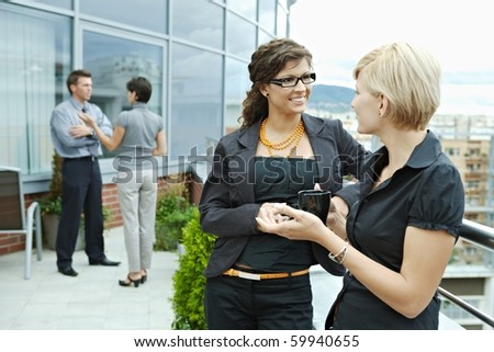 Businesswomen having break on office terrace outdoor drinking coffee talking.