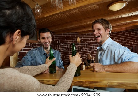 Young men laughing at woman drinking beer in pub.?