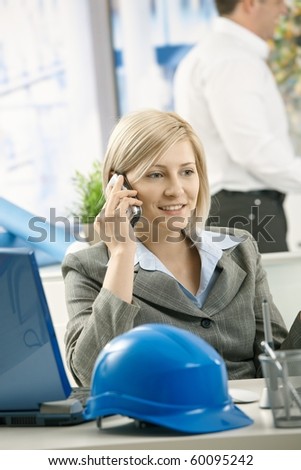 Smiling professional talking on phone in architect office.?