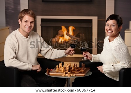 Young couple playing chess at home on a cold winter day.