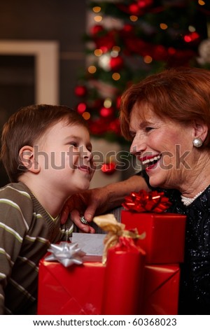 Portrait of happy grandmother and grandson looking to each other over christmas presents, smiling. ?