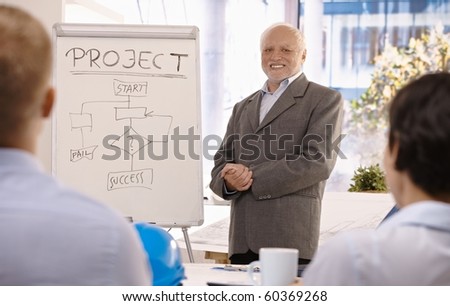 Experienced senior businessman training group about project success in office, smiling.?