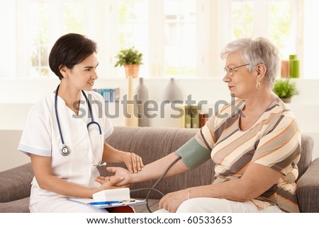 Female doctor measuring blood pressure of senior woman at home.?
