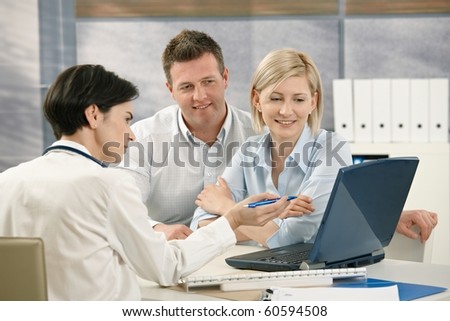 Medical doctor showing results to patients on computer in office.?