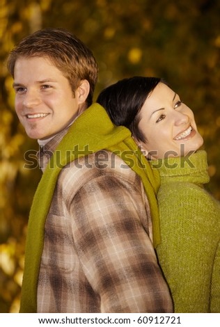 Portrait of happy, smiling couple standing back to back in autumn park.?
