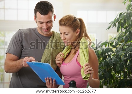 Young woman checking training plan with her personal trainer at home.