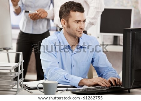 Casual businessman working in office, sitting at desk, typing on keyboard, looking at computer screen.?