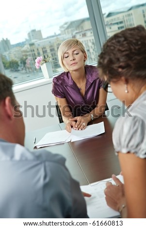 Woman applicant worrying during job interview.  Over the shoulder view.