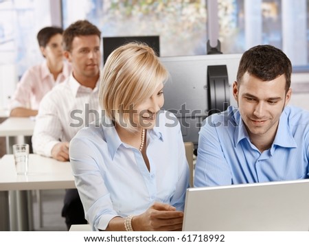 Young business people sitting at desk, using computer at business training, smiling.?