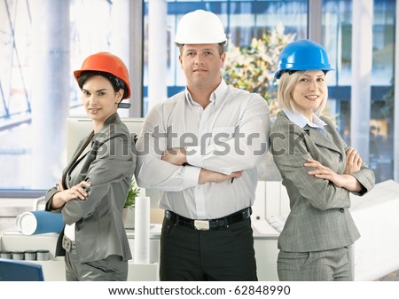 Architect team wearing hardhat in office, posing for portrait, looking at camera, smiling.?