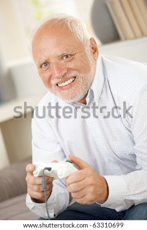 Older man having fun with computer game, smiling happily.?