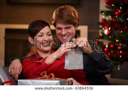 Happy young couple holding christmas presents, smiling. ?