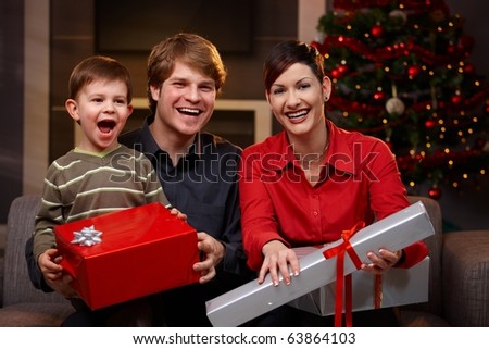 Portrait of happy family sitting at couch, holding christmas gifts, laughing.?