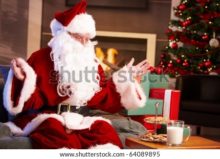 Satisfied Santa Claus sitting at fireplace happy to get milk and chocolate chip cookies.?