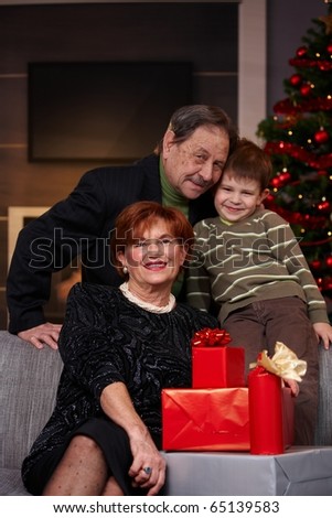 Portrait of small boy and happy grandparents with gifts at christmas, smiling.?
