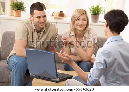 Advisor and smiling couple in discussion in bright living room.?