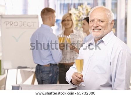 Portrait of senior businessman celebrating project done in office with champagne, employees talking in background.?