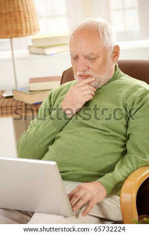 Senior man sitting at home, looking at screen of laptop computer, thinking.?