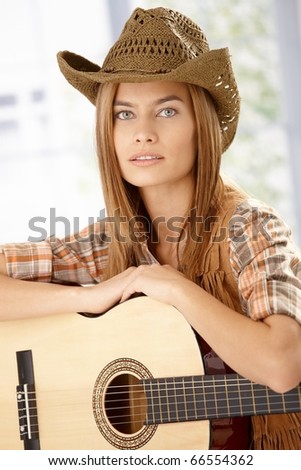Portrait of attractive girl with guitar and western hat.?