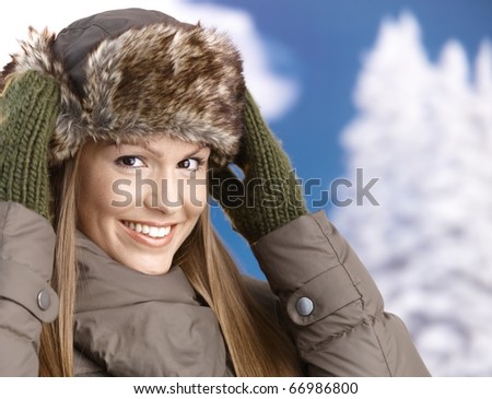 Young attractive woman dressed up for winter fun in coat, fur-hat and gloves, enjoying winter, smiling.?