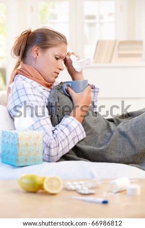 Young woman laying in bed, caught cold, feeling bad, drinking tea, taking vitamins.?