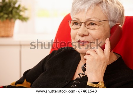 Closeup portrait of senior lady on landline phone call, smiling.